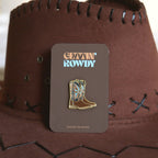 Cowboy boot enamel pin badge on a brown card with 'Gettin' Rowdy' text, against a brown cowboy hat