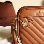 Brown quilted handbag with cowboy boot and hat pin badges