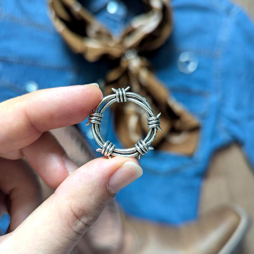 Hand holding a silver barbed wire ring with blurred background