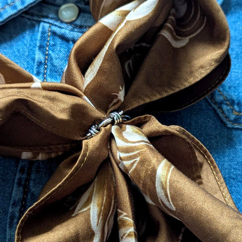 Brown patterned scarf tied around a blue denim jacket with barbed wire slider
