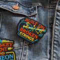 Denim jacket with colorful embroidered patch on a dark denim background
