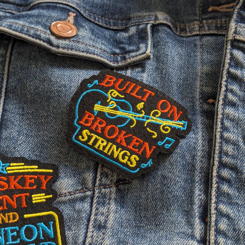 Denim jacket with colorful embroidered patch on a dark denim background