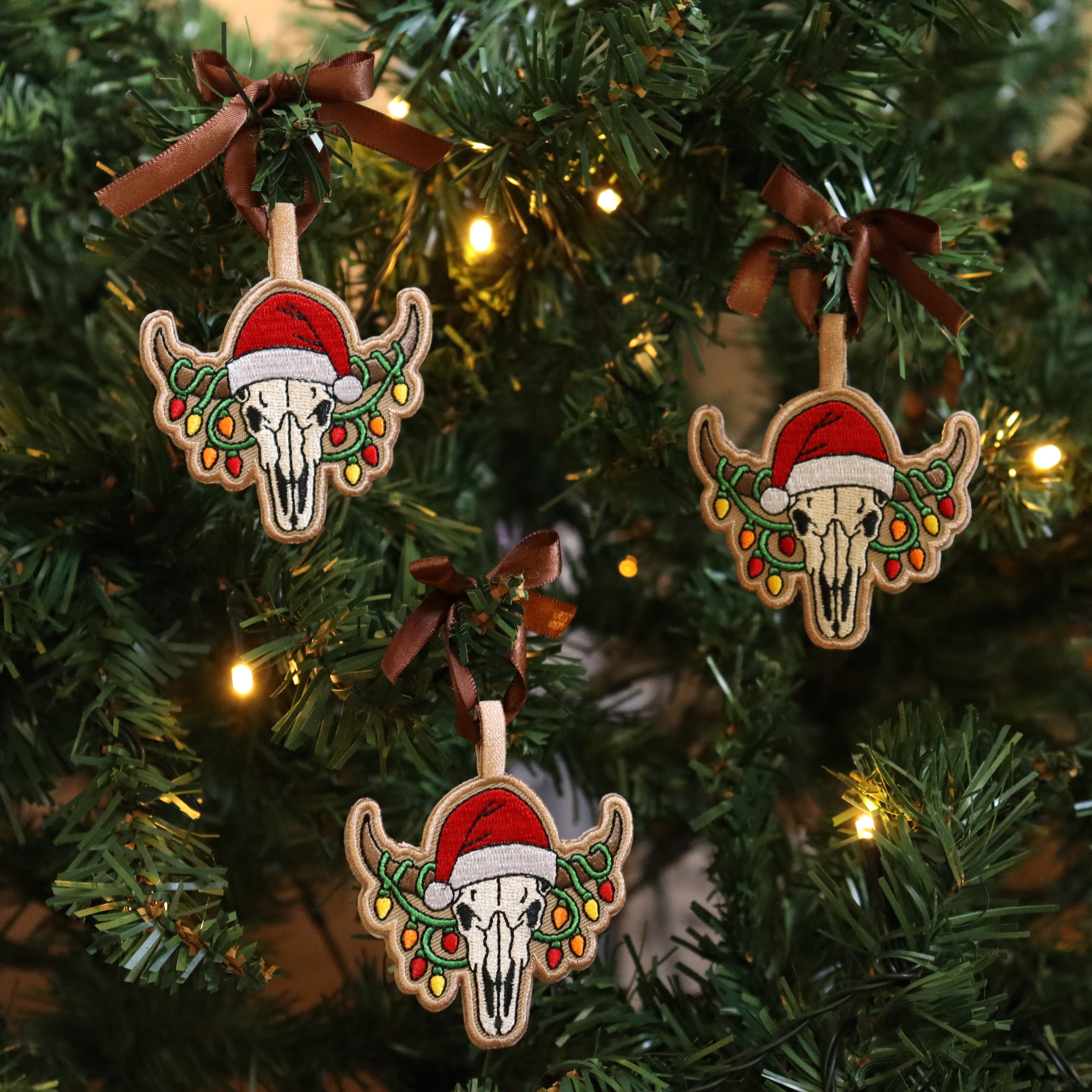 Three Christmas-themed skull ornaments with Santa hats on a decorated tree.