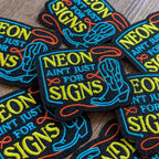 Neon-themed patches with colorful text and graphics on a wooden surface