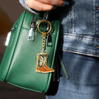 Green handbag with a keychain featuring a cowboy boot design