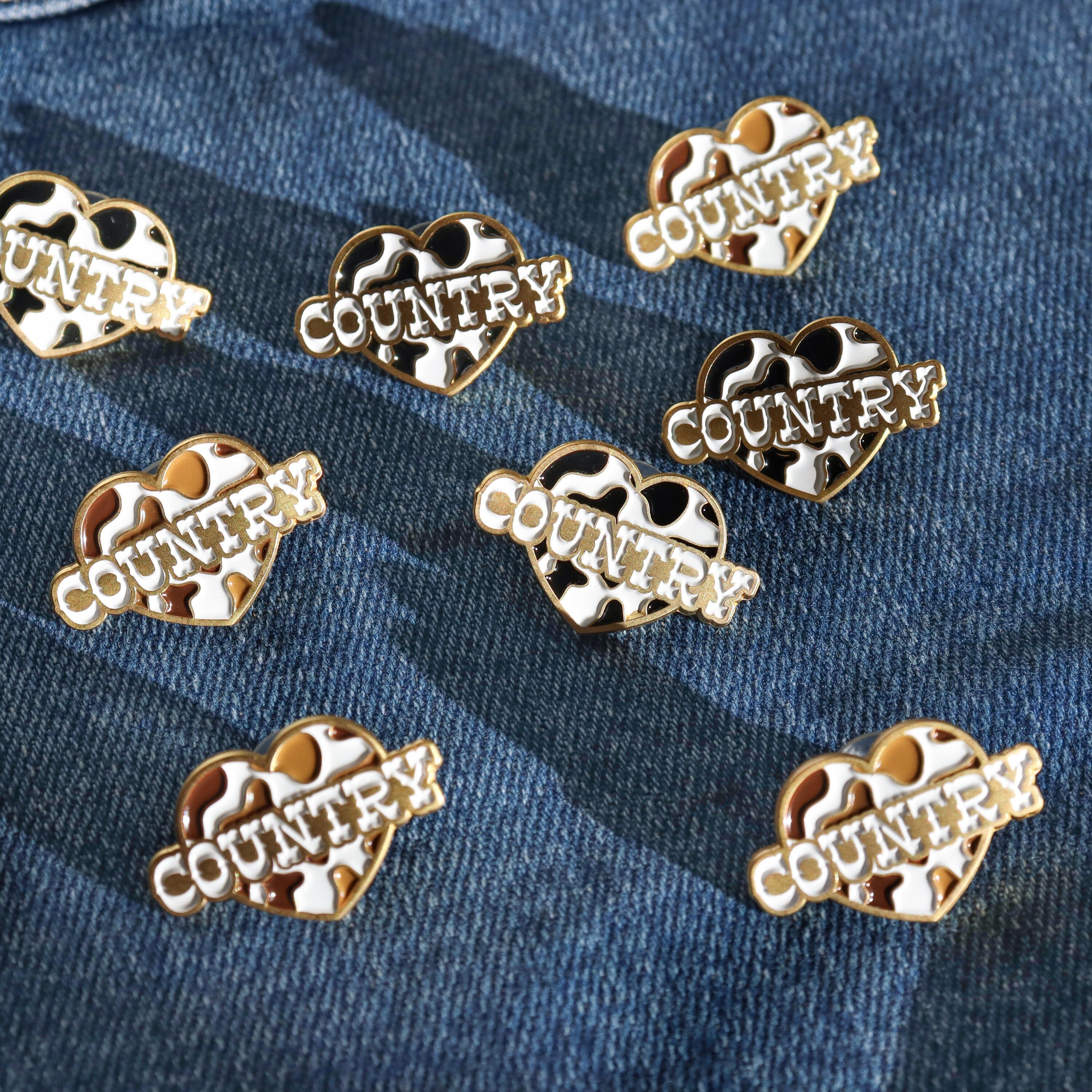 Cow print enamel pin for country music fans on a denim jacket