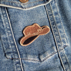 Brown cowboy hat patch on a blue denim jacket