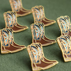 Cowboy boot pins on a green textured background